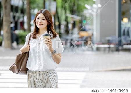 テイクアウトコーヒーを持って街を歩く日本人女性 140843406