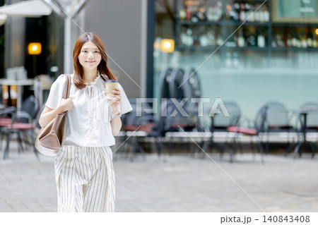 テイクアウトコーヒーを持って街を歩く日本人女性 140843408