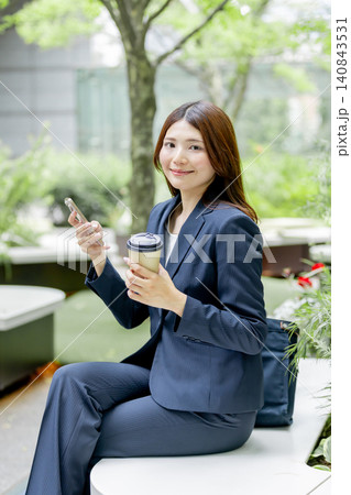 スマートフォンとコーヒーで休憩するビジネスウーマン スマートフォンとコーヒーで休憩するビジネスウーマン 140843531