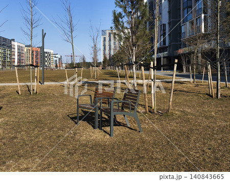 Park benches stand along path in residential courtyard outdoors. Urban space includes seating and landscaping for relaxation. City environment reflects community, lifestyle, Park benches stand along path in residential courtyard outdoors. Urban space includes seating and landscaping for relaxation. City environment reflects community, lifestyle, 140843665