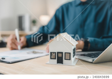 Estate property residential investment domestic construction insurance mortgage writing, professional man handles small house model and laptop for home purchase document management tasks Estate property residential investment domestic construction insurance mortgage writing, professional man handles small house model and laptop for home purchase document management tasks 140843699