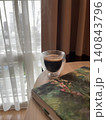 Morning Espresso in Double Wall Glass Next to Book by Window 140843796