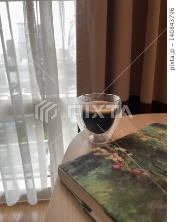Morning Espresso in Double Wall Glass Next to Book by Window Morning Espresso in Double Wall Glass Next to Book by Window 140843796