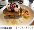 Gourmet French toast topped with fresh berries, whipped cream, and edible flowers on a white plate 140843798
