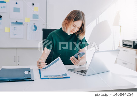 Happy female entrepreneur using smart phone in office. Happy female entrepreneur using smart phone in office. 140844254