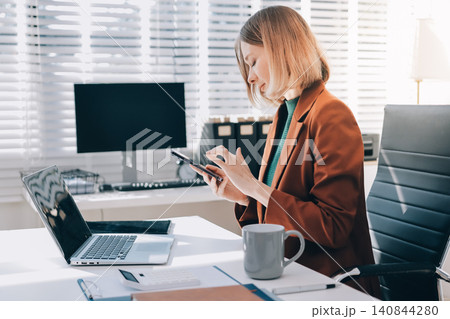 Woman smiling to herself as she works in an office Woman smiling to herself as she works in an office 140844280