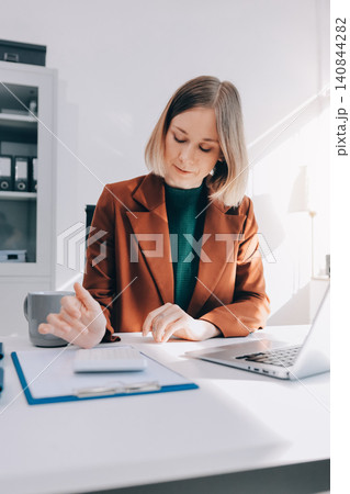 Woman smiling to herself as she works in an office Woman smiling to herself as she works in an office 140844282