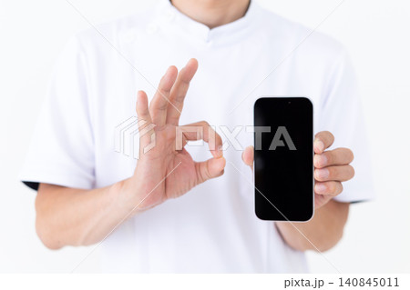 スマホを持って丸のポーズをする白衣を着たミドル男性の鍼灸師・整体師 スマホを持って丸のポーズをする白衣を着たミドル男性の鍼灸師・整体師 140845011