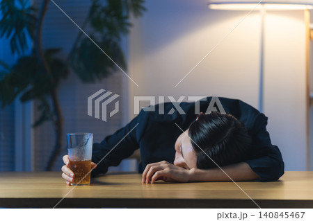暗い部屋で酔い潰れる女性。お酒、ショック、がっかり、落ち込む、やけ酒、酔う、アルコール、居酒屋 暗い部屋で酔い潰れる女性。お酒、ショック、がっかり、落ち込む、やけ酒、酔う、アルコール、居酒屋 140845467