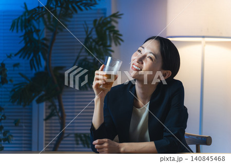 暗い部屋でお酒を飲む女性。ビール、ウイスキー、飲み会、居酒屋、バー、スナック、宅飲み 140845468