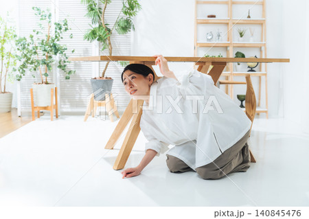 テーブルの下に潜る女性。地震、災害、非難、防災、驚く、怯える、怖い、緊急地震速報 140845476