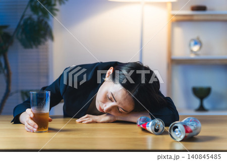 暗い部屋で酔い潰れる女性。お酒、ショック、がっかり、落ち込む、やけ酒、酔う、アルコール、居酒屋 140845485