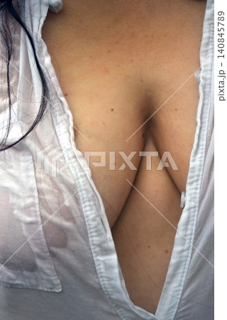 Closeup of sensual woman in wet shirt near a palm tree in a tropical garden Closeup of sensual woman in wet shirt near a palm tree in a tropical garden 140845789