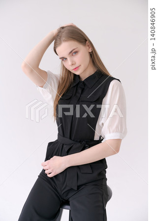 Relaxed Young Woman Sitting on a Stool in a Black Jumpsuit Lifestyle Relaxed Young Woman Sitting on a Stool in a Black Jumpsuit Lifestyle 140846905
