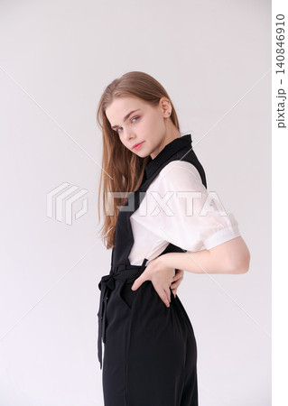 Poised Young Woman in Side View with Hand on Hip in a Black Jumpsuit 140846910