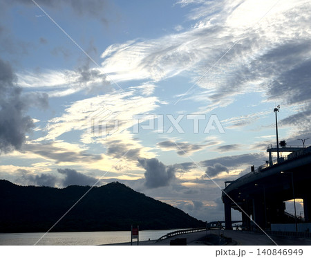 Dramatic clouds over a coastal highway and silhouetted island at dusk Dramatic clouds over a coastal highway and silhouetted island at dusk 140846949