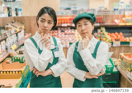 スーパーマーケットで腕を組んで考える2人の女性店員 スーパーマーケットで腕を組んで考える2人の女性店員 140847139