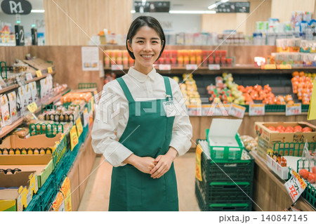 スーパーマーケットの野菜売り場で手を添えて案内する若い女性店員 スーパーマーケットの野菜売り場で手を添えて案内する若い女性店員 140847145