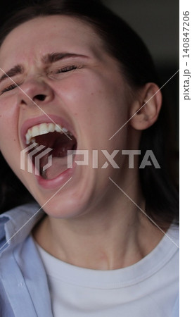 Vertical video Close up of a young stressed woman shouting on living room background. Motions concept. Woman's reaction to bad news. Vertical video Close up of a young stressed woman shouting on living room background. Motions concept. Woman's reaction to bad news. 140847206