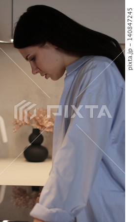 Vertical video Woman is upset and crying while standing in the kitchen after a family quarrel. Relationship crisis. 140847245