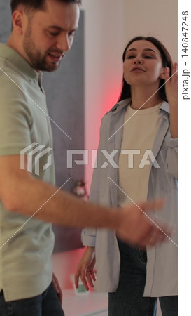 Vertical video A man and a woman are arguing in the living room, showing emotions and stress. Relationship crisis. 140847248