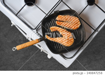 Grilling salmon fillets on stovetop with grill pan in kitchen 140847258