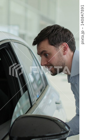 Vertical video Man buyer choosing examine dreaming male auto showroom touch new car. Concept of car shopping, buying, and dealership. Vertical video Man buyer choosing examine dreaming male auto showroom touch new car. Concept of car shopping, buying, and dealership. 140847891
