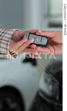 Vertical video Close up woman hand gives a car keys to buyer woman hand in car dealership close up. Concept of car shopping, buying, and dealership. Vertical video Close up woman hand gives a car keys to buyer woman hand in car dealership close up. Concept of car shopping, buying, and dealership. 140847963