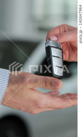 Vertical video Young man buying a car from a dealer. Car seller hands over the keys to the buyer. Auto business concept. Vertical video Young man buying a car from a dealer. Car seller hands over the keys to the buyer. Auto business concept. 140847964