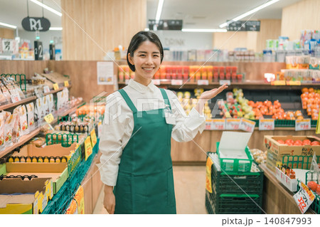 スーパーの青果コーナーで笑顔で案内ポーズをとる若い女性店員 スーパーの青果コーナーで笑顔で案内ポーズをとる若い女性店員 140847993