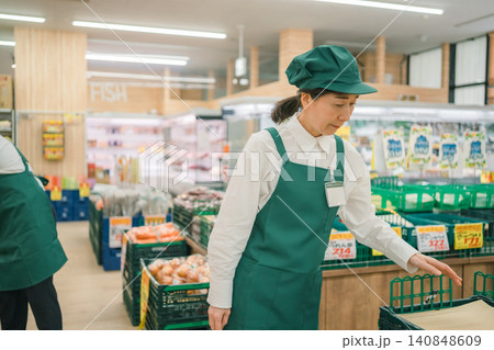 スーパーマーケットの野菜売り場で下を向いて作業する50代女性店員 スーパーマーケットの野菜売り場で下を向いて作業する50代女性店員 140848609