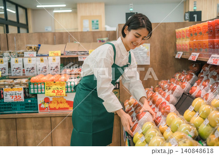 スーパーマーケットの果物売り場で両手でりんごを並べる女性店員 スーパーマーケットの果物売り場で両手でりんごを並べる女性店員 140848618