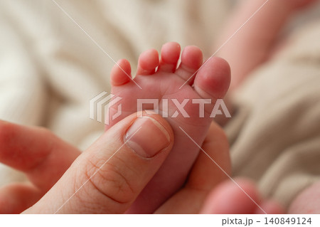 A beautiful, high-quality stock image showing a mother's thumb massaging a tiny newborn baby's foot. Concept of pediatric care, infant massage, maternal love, and body health. Close-up macro A beautiful, high-quality stock image showing a mother's thumb massaging a tiny newborn baby's foot. Concept of pediatric care, infant massage, maternal love, and body health. Close-up macro 140849124