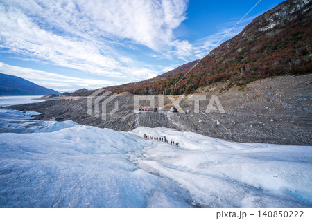 Perito moreno glacier patagonia los glaciares national park hikers crossing blue ice under wide sky by mountain Perito moreno glacier patagonia los glaciares national park hikers crossing blue ice under wide sky by mountain 140850222