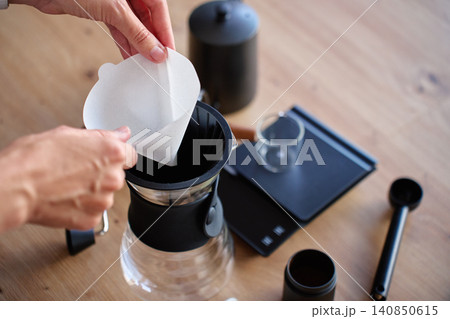 Hands placing paper filter into pour over coffee dripper 140850615
