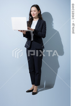 水色背景でパソコンを持つ笑顔でタイピングするスーツの日本人ビジネス女性、DXやAI、業務改善イメージ 水色背景でパソコンを持つ笑顔でタイピングするスーツの日本人ビジネス女性、DXやAI、業務改善イメージ 140851449