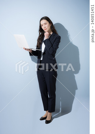 水色背景でノートパソコンをつ笑顔で考えるスーツの日本人ビジネス女性、DXやAI、業務改善イメージ全身 水色背景でノートパソコンをつ笑顔で考えるスーツの日本人ビジネス女性、DXやAI、業務改善イメージ全身 140851451