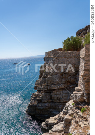 Historic Venetian fortress on steep rocky cliff over blue sea on Spinalonga island Greece Historic Venetian fortress on steep rocky cliff over blue sea on Spinalonga island Greece 140852304