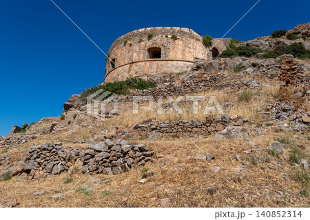 Round Venetian fortress bastion on rocky hillside under clear sky on Spinalonga Greece Round Venetian fortress bastion on rocky hillside under clear sky on Spinalonga Greece 140852314