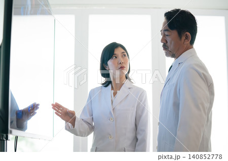 画面を見ながら会話する男女医師のグループ。医師、科学者、研究者、カンファレンス、相談、白衣、病院 画面を見ながら会話する男女医師のグループ。医師、科学者、研究者、カンファレンス、相談、白衣、病院 140852778