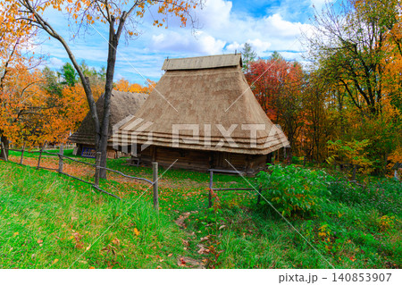 Traditional Ukrainian wooden house with thatched roof in autumn landscape 140853907