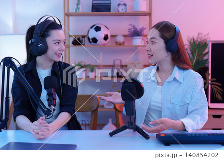 Two Asian women recording podcast episode in creative home studio 140854202