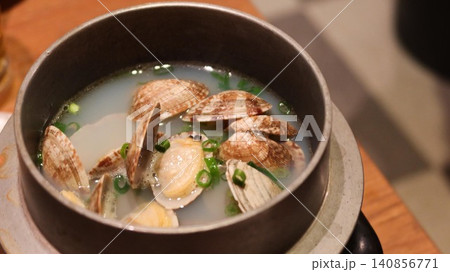 close up of Sake Steamed Clams in a pot served in a traditional metal pot, featuring fresh clams with open shells in a clear, savory broth, garnished with chopped green onions with copy space close up of Sake Steamed Clams in a pot served in a traditional metal pot, featuring fresh clams with open shells in a clear, savory broth, garnished with chopped green onions with copy space 140856771