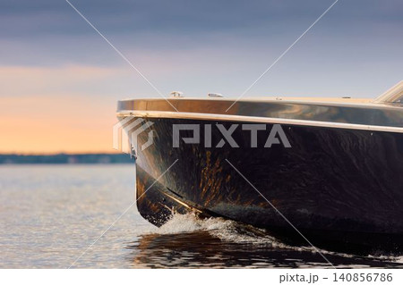 Incredible reflection on the glossy side of a modern motorboat at sunset, the Gulf of Finland, magic reflections on water surface Incredible reflection on the glossy side of a modern motorboat at sunset, the Gulf of Finland, magic reflections on water surface 140856786