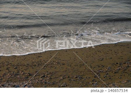 Waves gently lap against the rocky shoreline at dusk in a tranquil coastal landscape 140857534