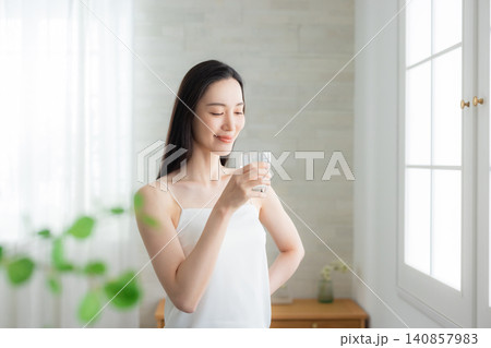 窓辺で水を飲む若い女性　 140857983