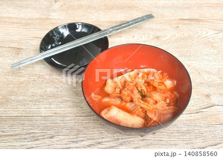 Kimchi pickled cabbage with sesame in salt Korean salad in red cup on table Kimchi pickled cabbage with sesame in salt Korean salad in red cup on table 140858560