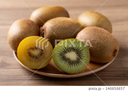 Fresh green and gold kiwi fruit on a wooden plate over a wooden background. Healthy fruit Fresh green and gold kiwi fruit on a wooden plate over a wooden background. Healthy fruit 140858857
