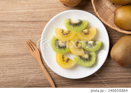 Sliced gold and green kiwi fruit on a white plate ready to eating. Healthy fruit. Table top view Sliced gold and green kiwi fruit on a white plate ready to eating. Healthy fruit. Table top view 140858864