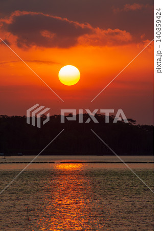 Beautiful golden sunset over the river with a small boat and sun reflection on the water. 140859424